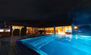 Luxuriöses Hotel mit beheiztem Außenpool und moderner Wellnessoase bei Nacht in den österreichischen Alpen.