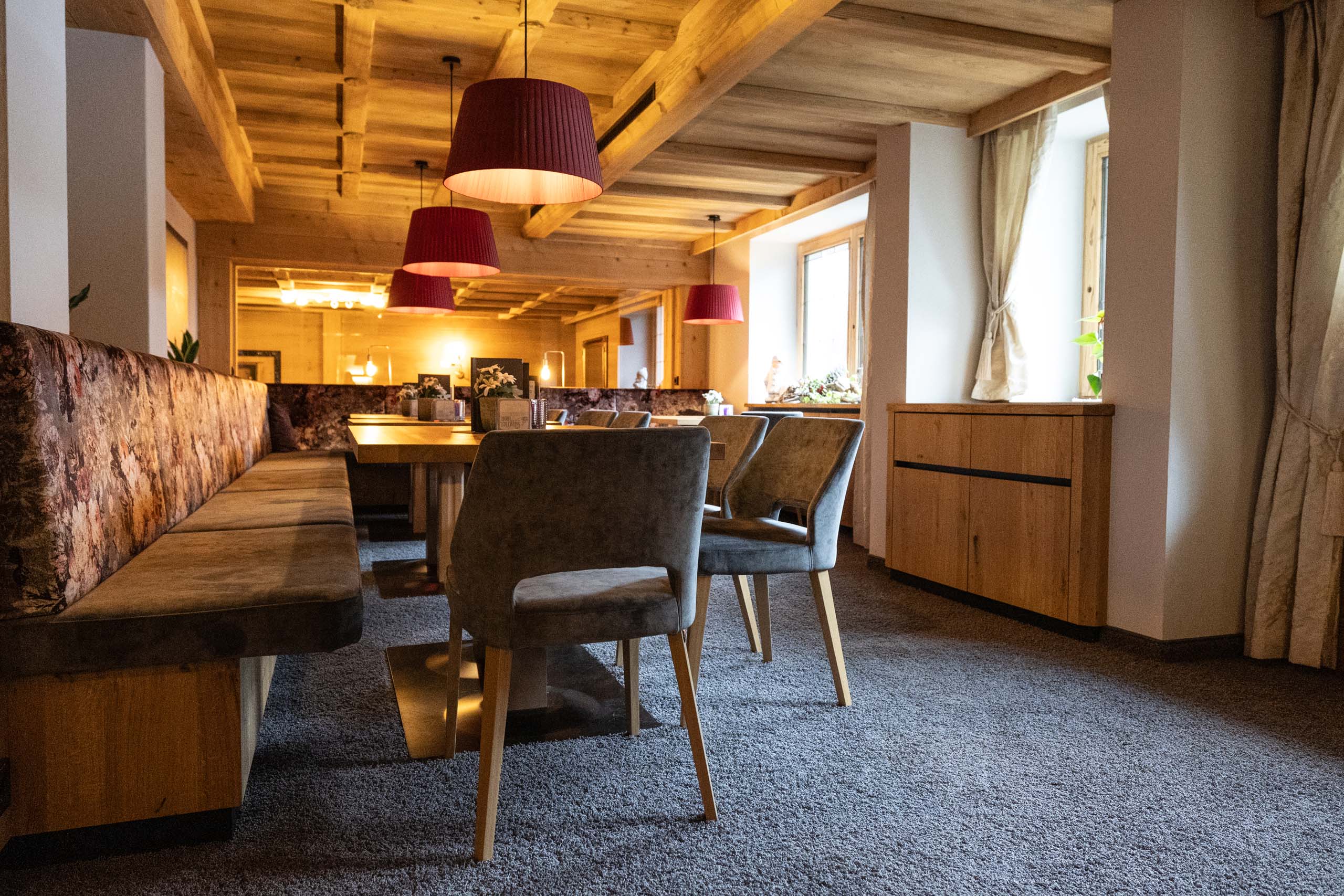 Gemütliches Restaurant in einem alpinen Hotel mit Holzdecke, komfortablen Stühlen und warmem Ambiente, ideal für kulinarische Genüsse in den Alpen.