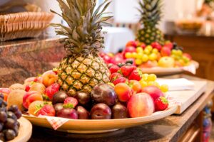 Frischer Obstteller mit Ananas, Äpfeln, Erdbeeren, Pfirsichen und Trauben, abwechslungsreiche Auswahl an Obst für gesunden Genuss.
