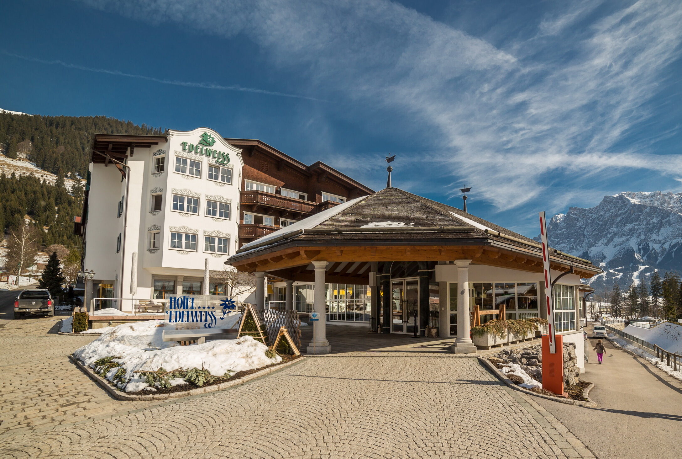 Elegante hotelkamer met comfortabel bed, houten inrichting en gezellige zithoek in een Oostenrijkse accommodatie van Edelweiss.at.