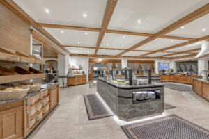 modernes Salatbuffet in einem eleganten Hotel, offen gestaltet mit Stein, viel Licht, internationale Speisen und gemütliche Atmosphäre, ideal für einen erholsamen Aufenthalt am Fuße der Zugspitze