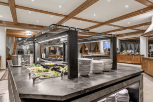 modernes Salatbuffet in einem eleganten Hotel, offen gestaltet mit Stein, viel Licht, internationale Speisen und gemütliche Atmosphäre, ideal für einen erholsamen Aufenthalt am Fuße der Zugspitze
